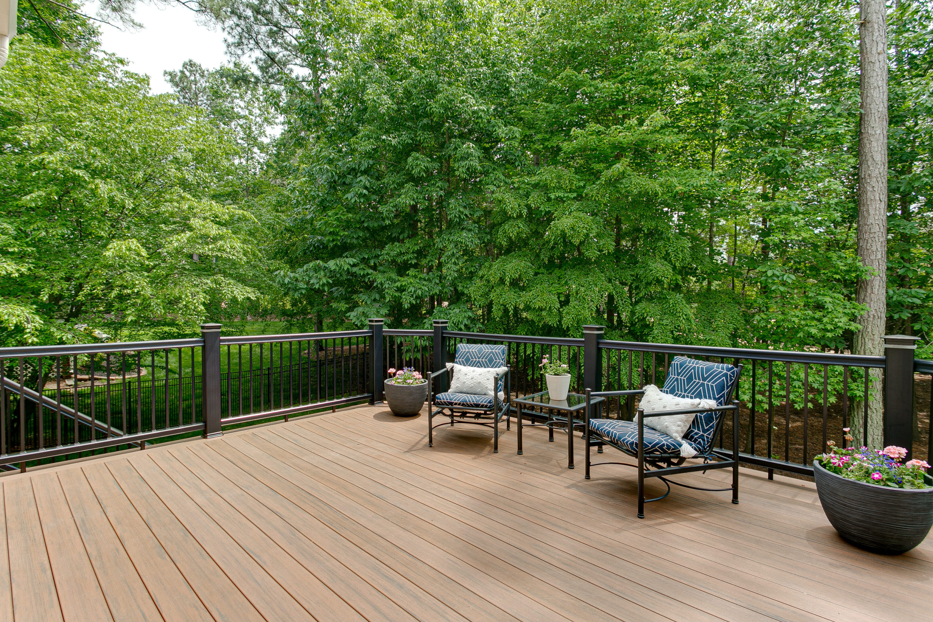 Beautiful Summer Staged Deck with Nature Woods and a Flower Pot A deck with chairs and tables on it from a custom deck builder in Kennesaw, GA